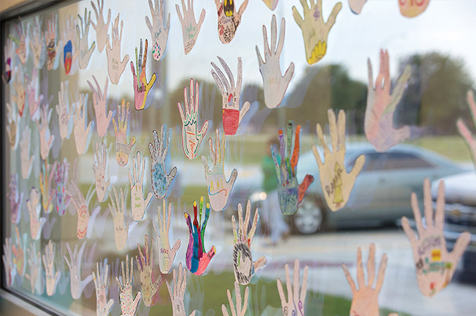 Handprints made of colorful paint adorn a window pane