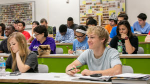 Students in a classroom listen attentively to the instructor