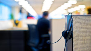 A pair of headphones hang on a cubicle wall