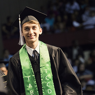A young man with a green stole walking across the stage