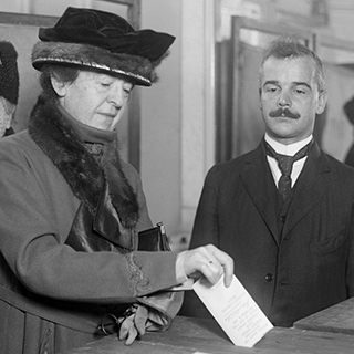 vintage photo of a woman putting a paper ballot in and ballot box