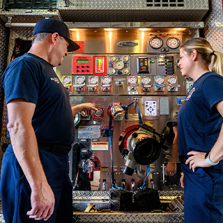 Father and daughter looking at fire truck equipment