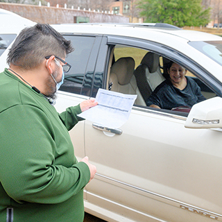 Man looking at student schedule of student waiting in a car