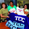 TCC staf hold merchandise with the new logo. Click for details