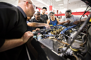 An instructor teaching students about the inner-workings of a car engine