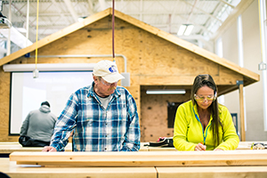 A man and a woman working on a construction project with wood pieces