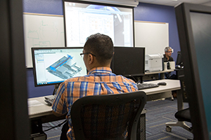 Student working at a computer building a 3D model of a building