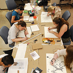 Overhead view of students around a rectangular table drawing