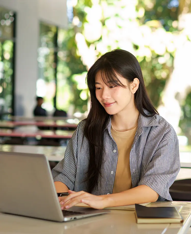 A young woman works on a laptop at a desk