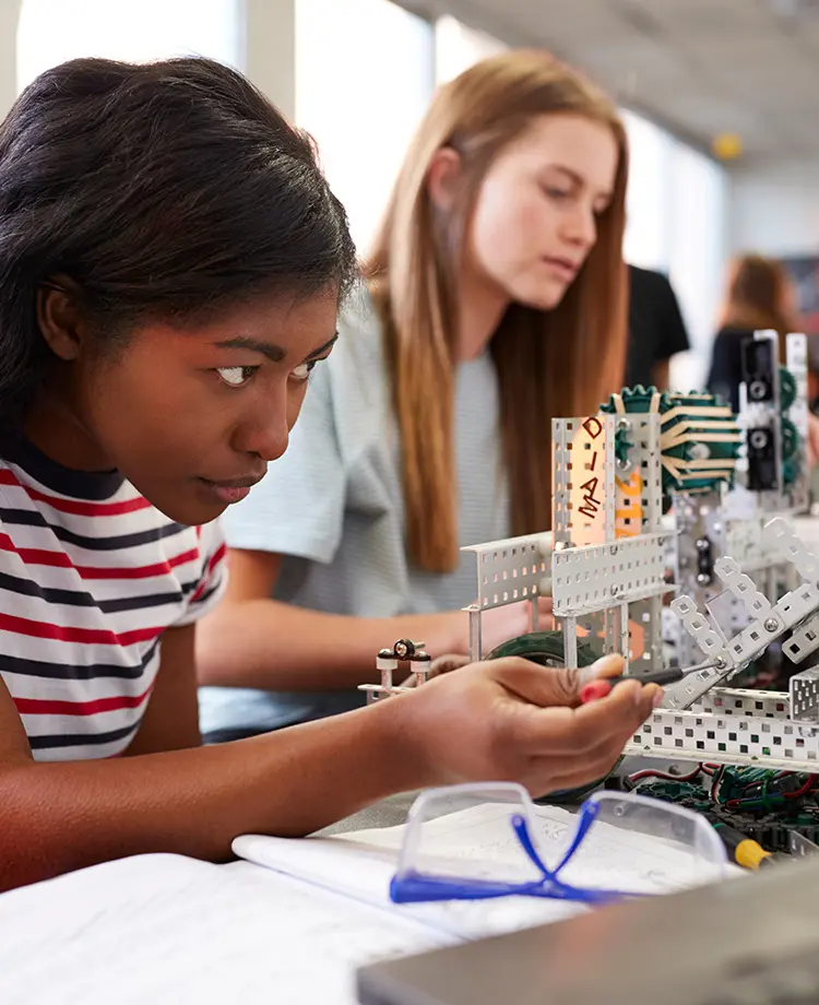 Students in a dual credit classroom work on building machine prototypes with erector sets