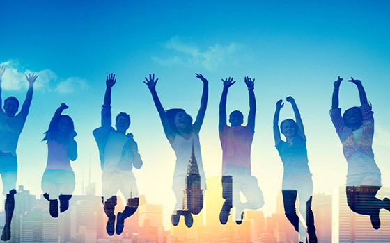 Student silhouettes jumping against a city skyline.