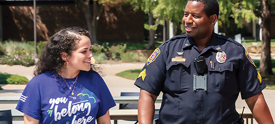 Male police officer walking next to a smiling young woman.