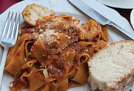 A plate of pasta in a red sauce, with fresh bread and cheese