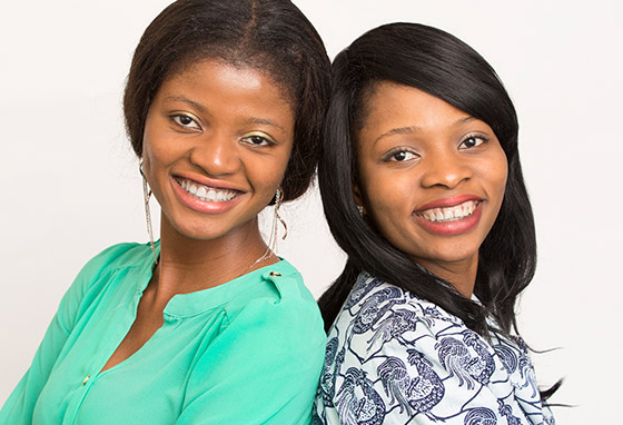 Joan and Priscilla stand back-to-back and smile