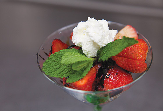 Strawberries, chocolate and whipped cream, garnished with a mint leaf, served in a martini glass.
