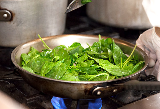 Verdant spinach leaves have just been added to a hot sauté pan