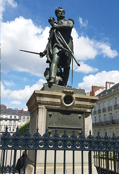 A large bronze statue atop a granite plinth bearing a plaque