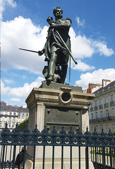 A large bronze statue atop a granite plinth bearing a plaque
