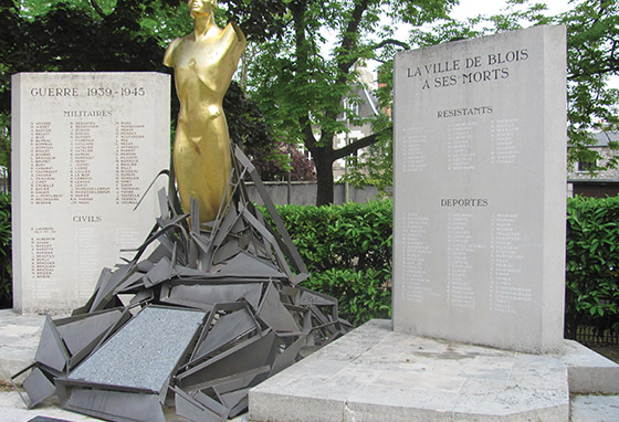 A shining bronze statue between two slabs bearing text