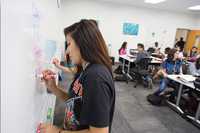 Crystal writes on the whiteboard at the front of the room