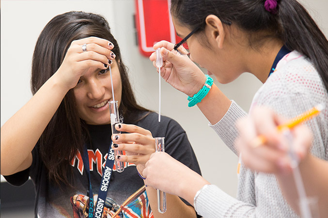 Crystal carefully adds fluid from a dropper to a test tube