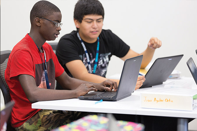 Juarel and another student work on laptops