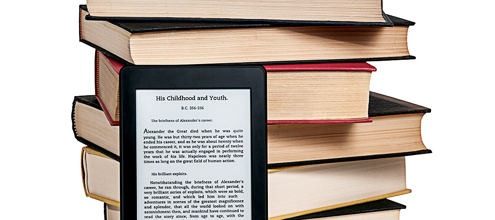 A Kindle e-reader leans on a pile of traditional books