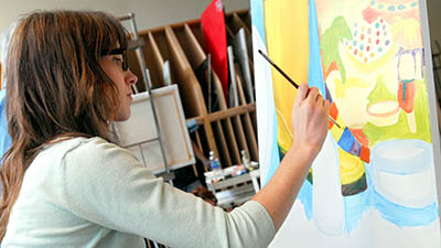 A student artist paints at an easel