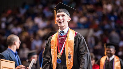 A graduate looks off into the distance, with a satisfied smile