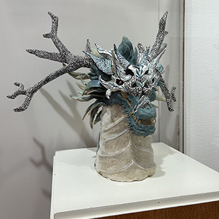 A picture of a ceramic artwork with a dragon head.