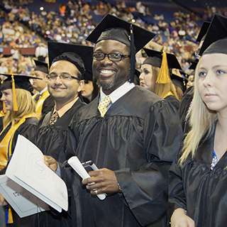 Male student smiling at the camera with his diploma