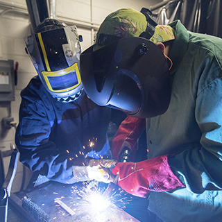 welders in protective head and body gear welding