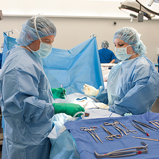 Students in surgical clothes working on a surgery