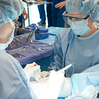 Students in surgical outfits working at a table