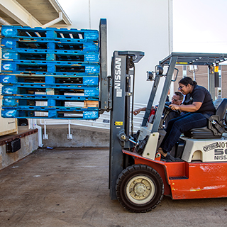 Student using a forklift to move a stck of pallets