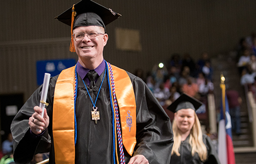 Student walking across stage with diploma