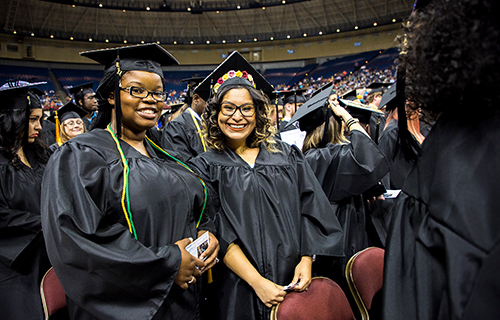 Two female students posing in their caps and gowns