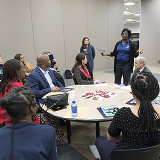 Group of people sitting around a table, listening to instructions
