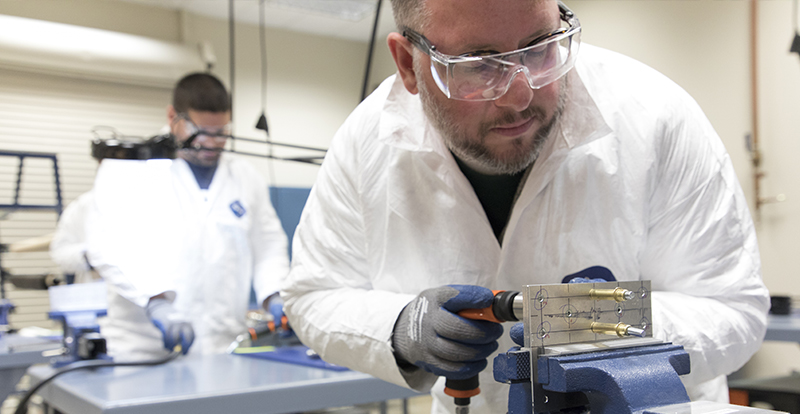 Man in a white lab coat drilling