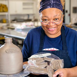 Green proudly holding a piece of her pottery