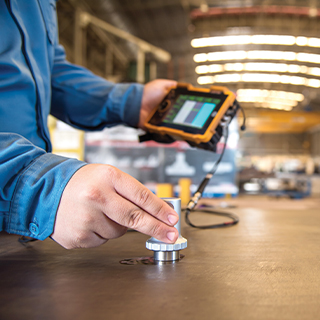 Hand holding a machine to test a metal surface