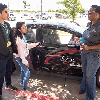 Students standing in front of an Oncor car