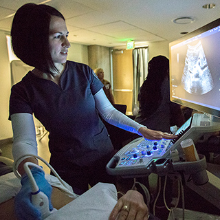 female student performing a sonogram on a patient's abdomen