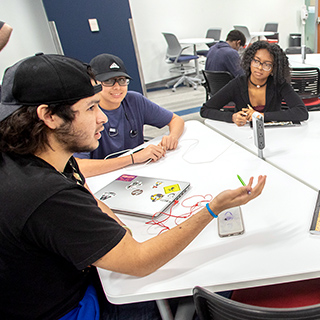 3 collaborating students around a table in a learning lab