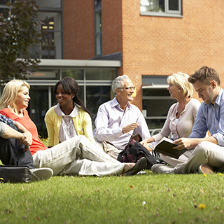 group of men and women of different ages sitting on the grass talking