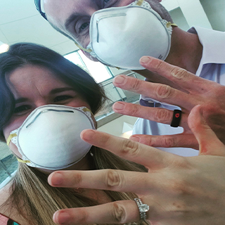 Couple posing in masks after being engaged