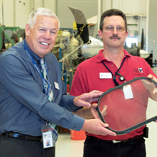 Two men holding a donated windshield