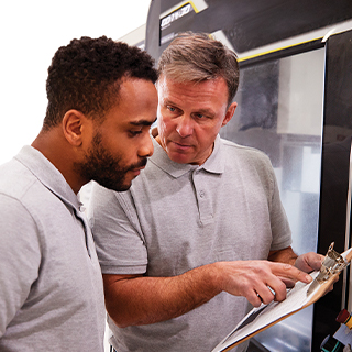 Man showing another man a paper on clipboard