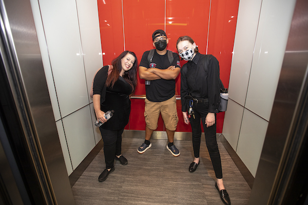 Three students in an elevator car. Katie is on the left.