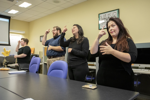 Four students in a sign language lab practice signing; Katie is on the right